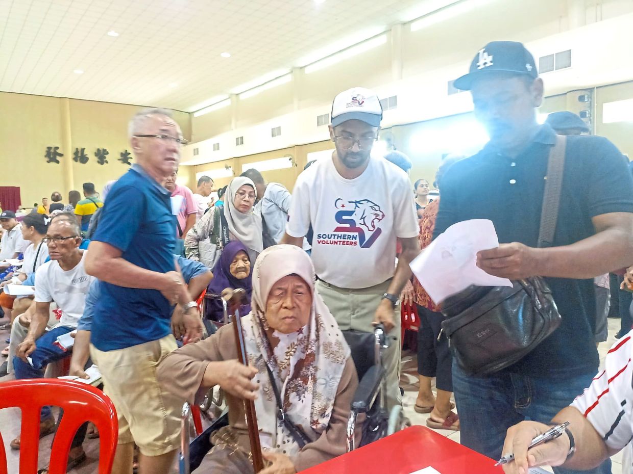 Surender (second from right) assisting a recipient during the distribution of Bantuan Kasih Johor in Yong Peng.