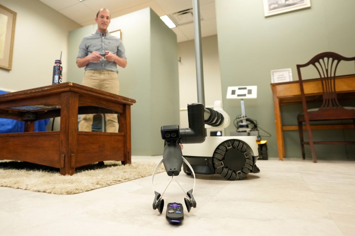 A robot operated by Shehab Attia, a robotics engineer at Hello Robot, reaches to pick up a TV remote during a demonstration at the University of New Hampshire, Tuesday, April 21, 2026, in Durham, N.H.