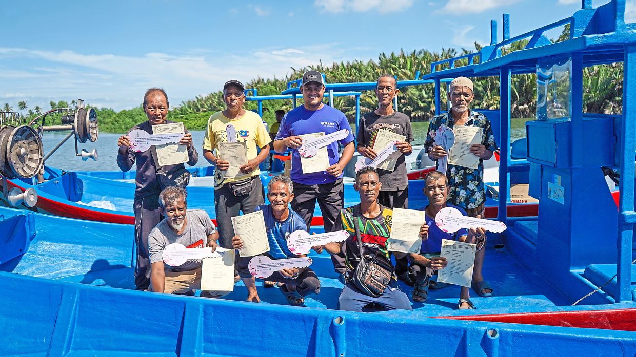 Some of the fishermen with mock keys after the asset handover which is part of Penang government’s Social Impact Management Plan.