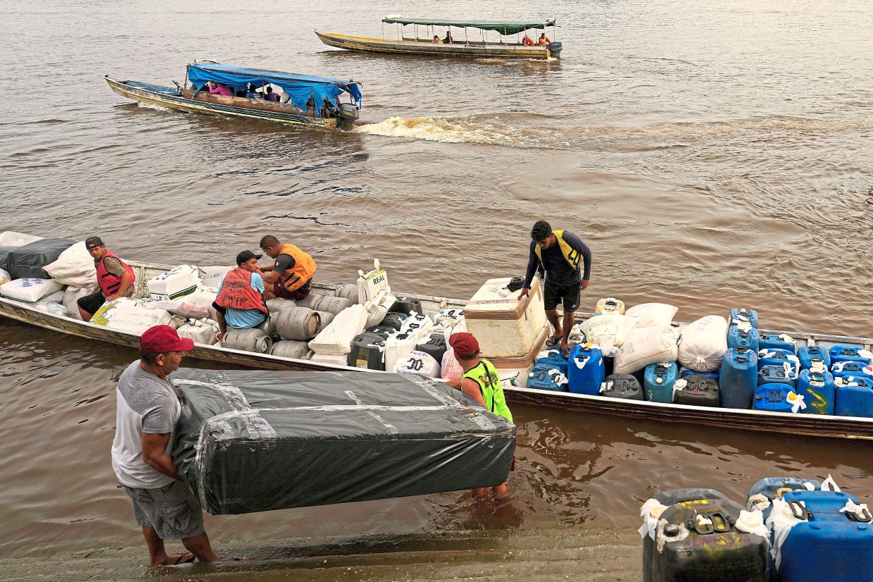 Boatmen operating catraia, a traditional boat used on the Oiapoque River, buying gasoline at a Petrobras gas station in a port in Oiapoque. — AP