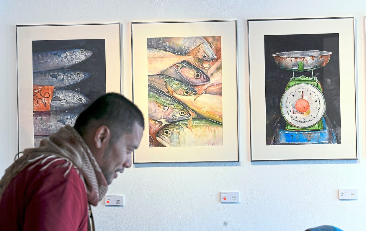 A visitor passes by a selection of Ryzalman's paintings at his debut solo exhibition 'Berapa Sekilo? Rhythm Of The Wet Market' at Awegallery in Petaling Jaya. Photo: The Star/Azhar Mahfof