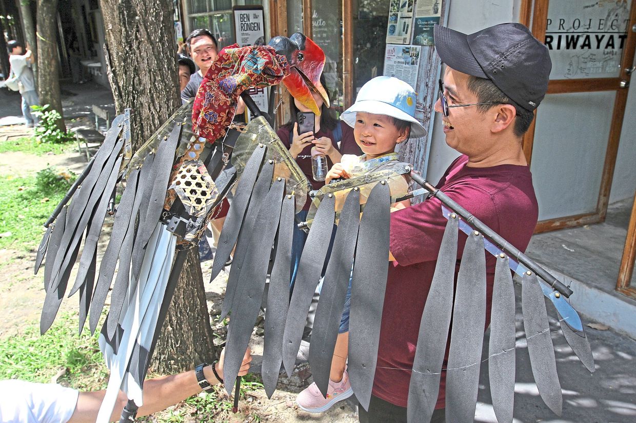 Visitor Brian Yong, 37, with daughter Jean, two, taking a closer look at a helmeted hornbill puppet at Hin Bus Depot, Penang.