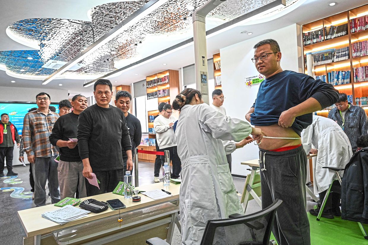 Male participants queueing up to get weighed and have their waist measured at a local community centre in Wuxi. — AFP 