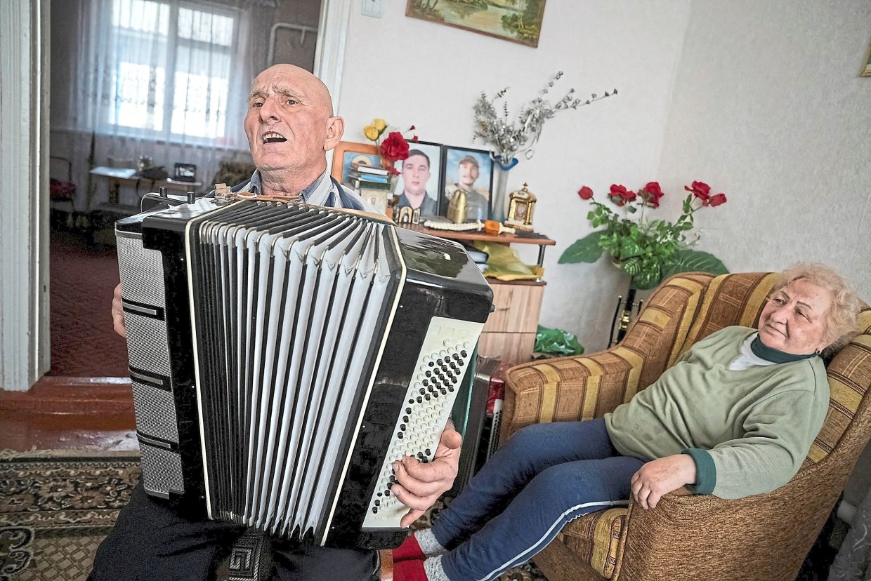 Hurin playing the accordion as his wife Olha listens in their house in the village of Khutory, Cherkasy region, Ukraine. — Reuters 