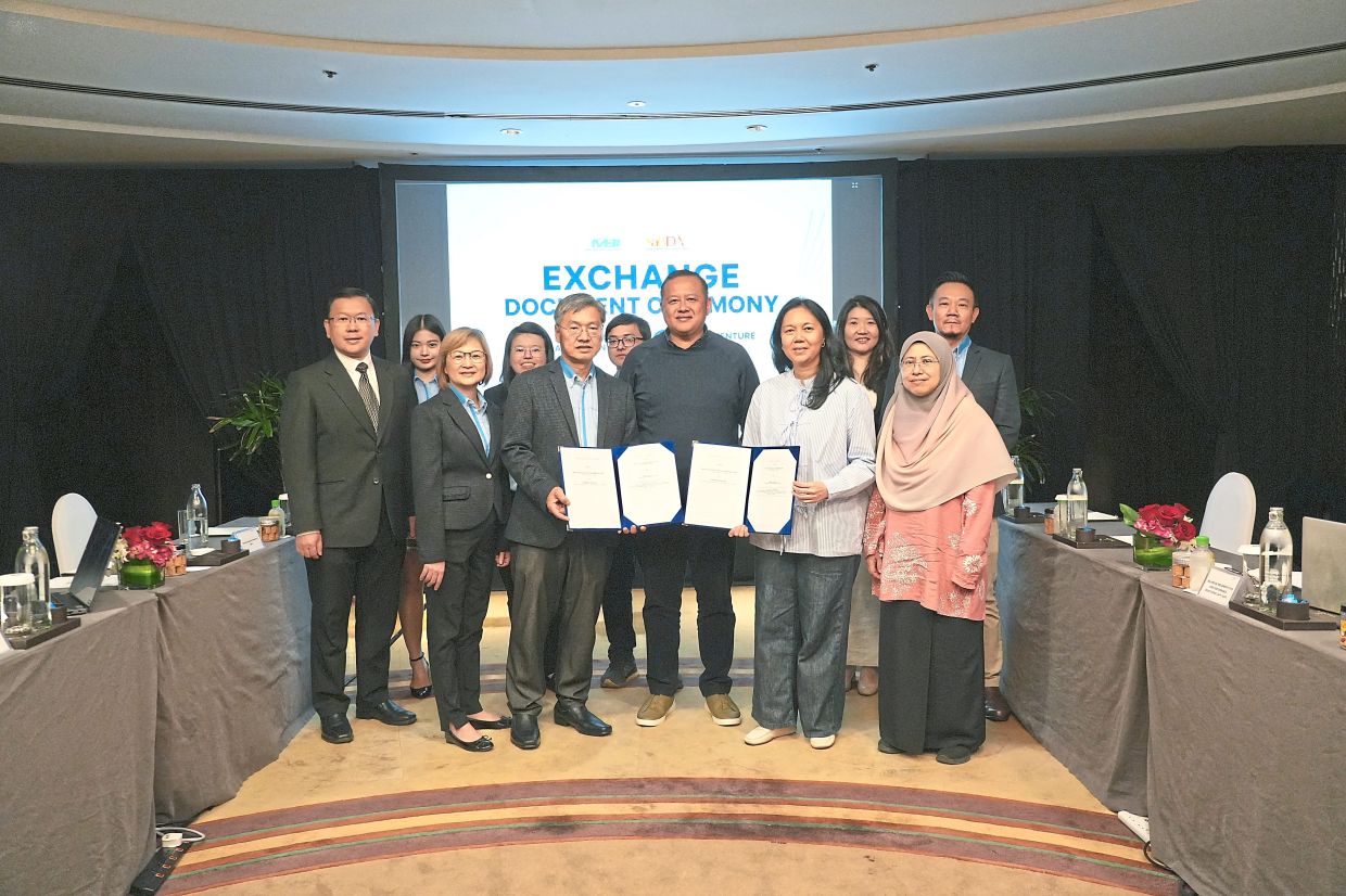 Zannifa Azura (front, second from right) and Teoh (front, third from left) exchanging agreements, witnessed by Rizam (centre). — Handout