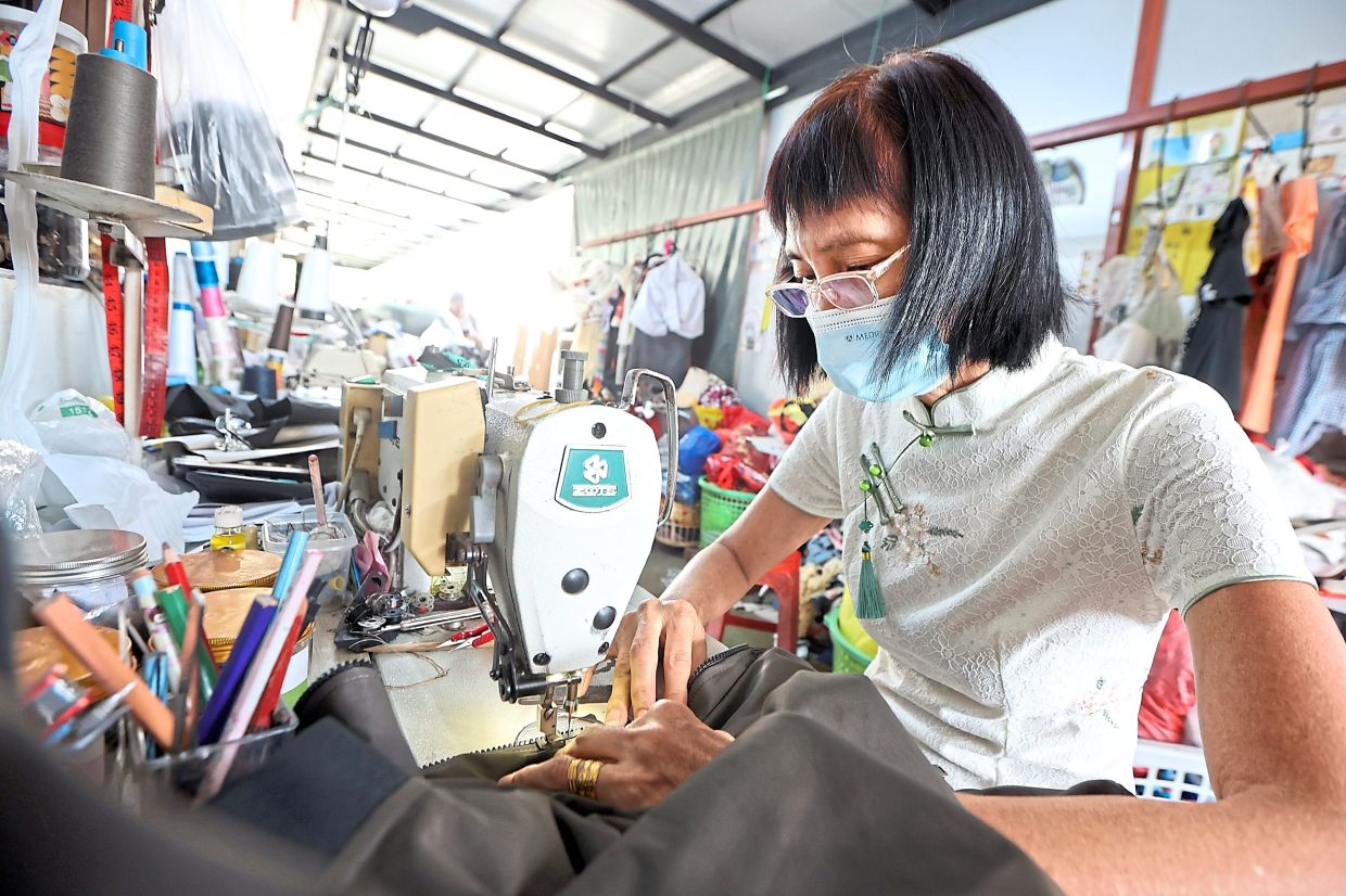 Ling sewing the zipper of a jacket at her house in Kulai.