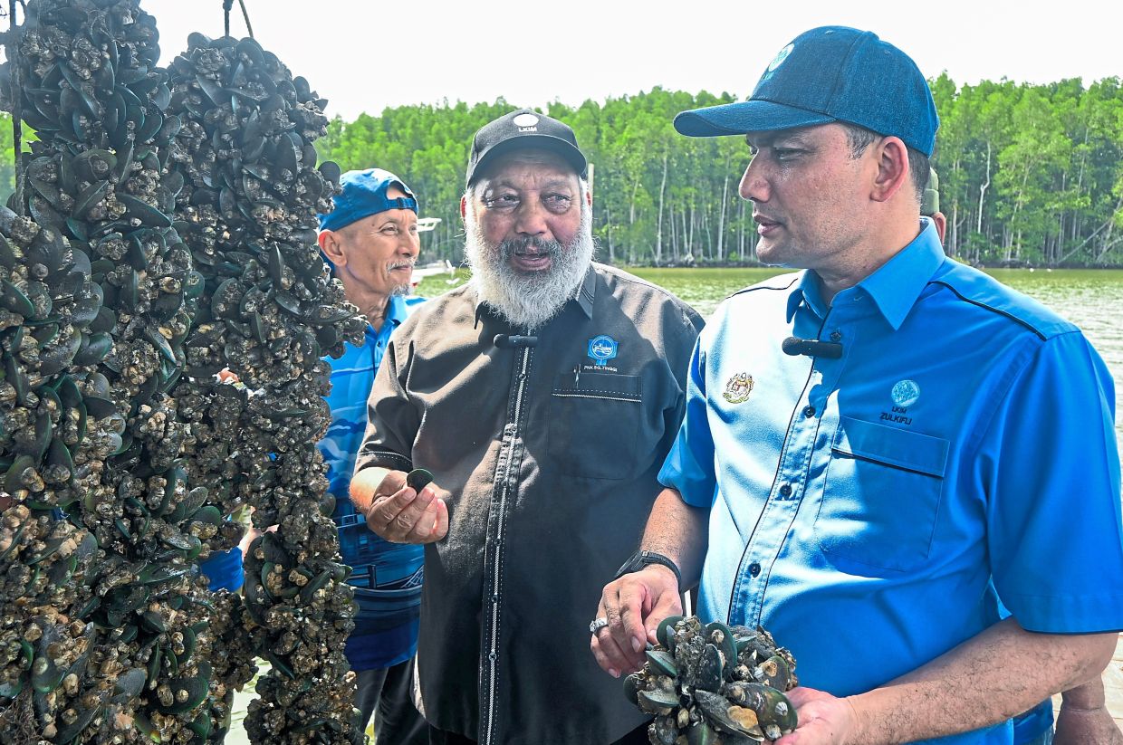 Ahmad Zulkifli (right) with Abu Salim (beside him) taking a closer look at the mussels grown by the Sungai Tinggi Fishermen’s Association.