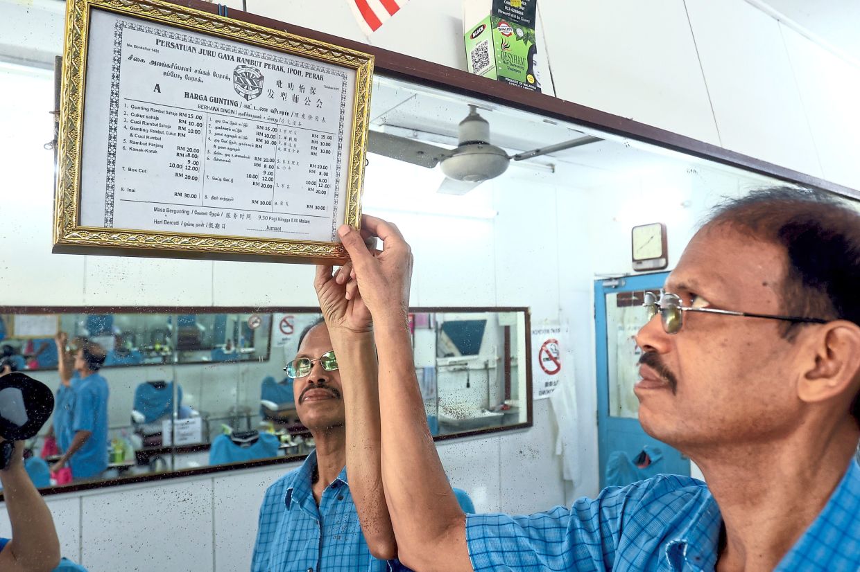 Anbarasu showing the Persatuan Jurugaya Rambut certificate along with rates for hair cuts, wash, applying henna and shave. His shop is in Jalan Tun Abdul Razak in Cherry Park, Ipoh.