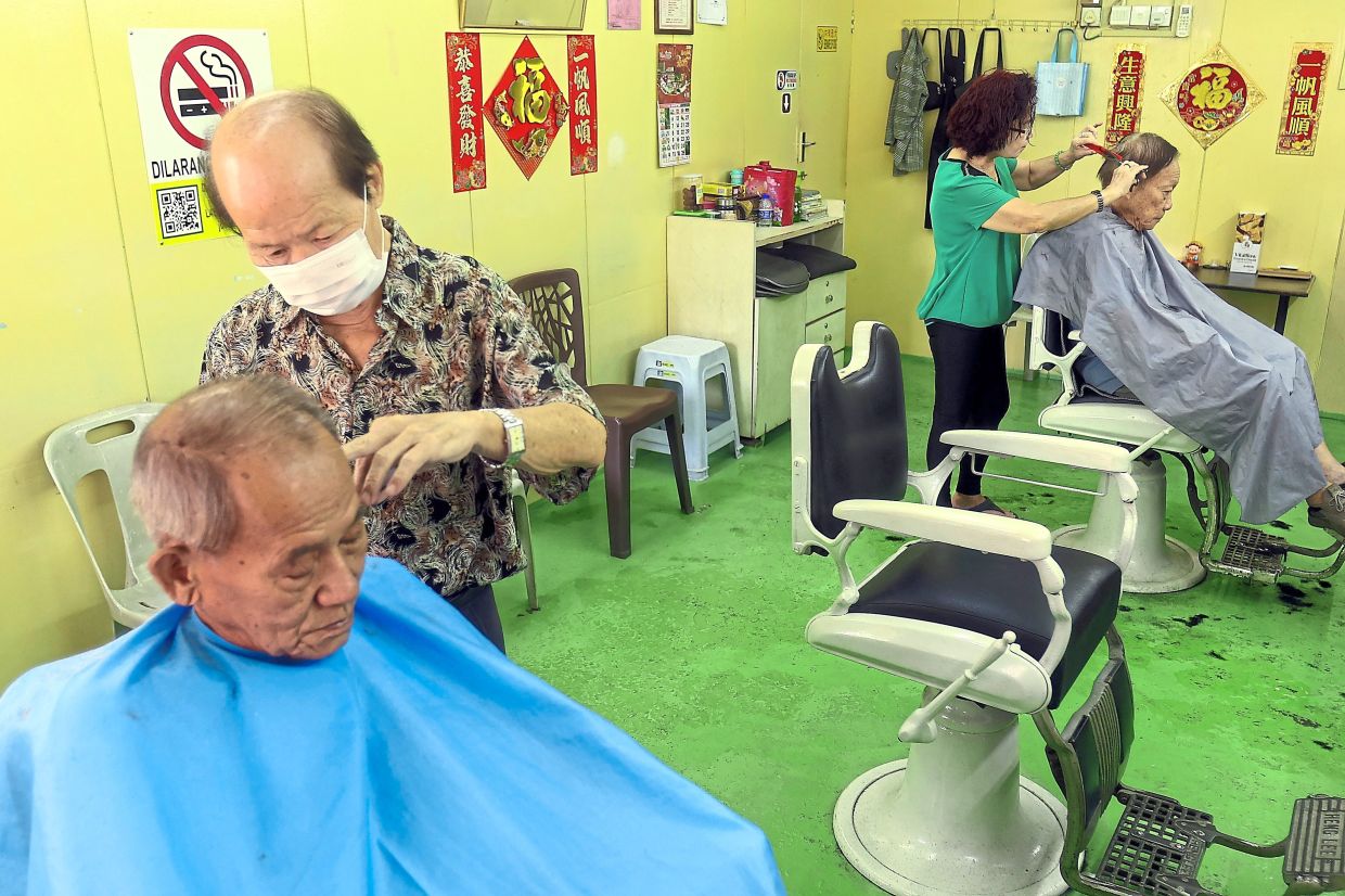 Chin (left) and Chu (in green) attending to customers at their Moon Moon barbershop.