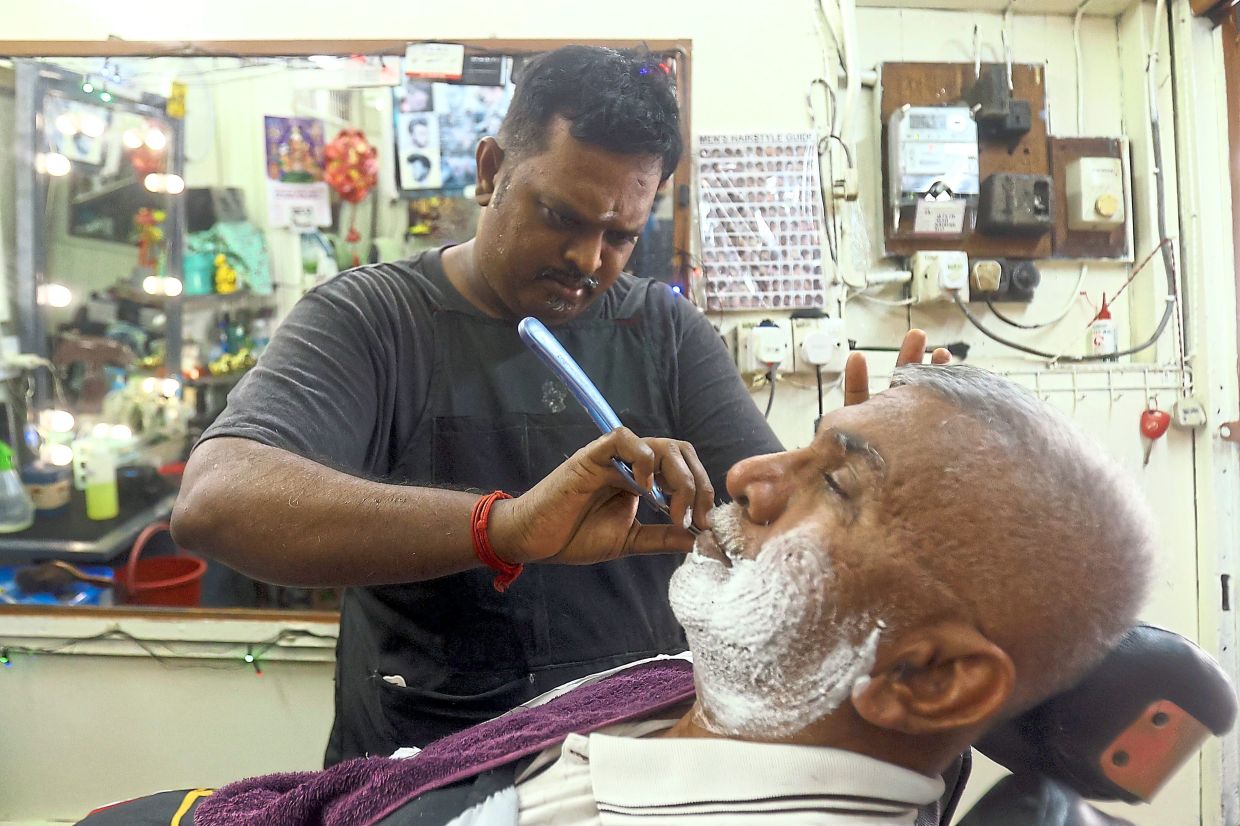 Selvaraj giving one of his regulars a shave at his barbershop located behind the Jalan Bijih Timah flats in Ipoh’s Old Town.