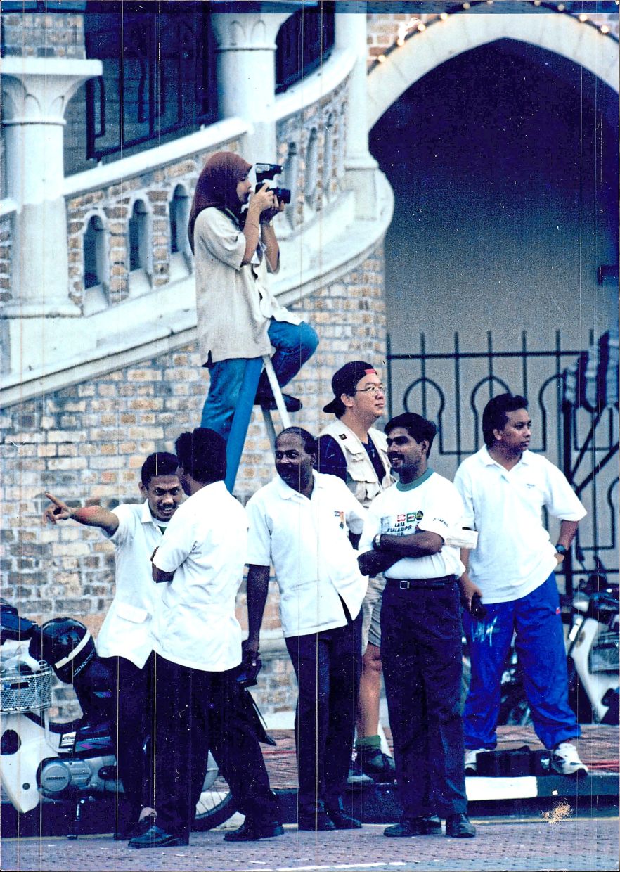 Azlina perched on a ladder while covering a high profile court case in Kuala Lumpur. Photo: Filepic