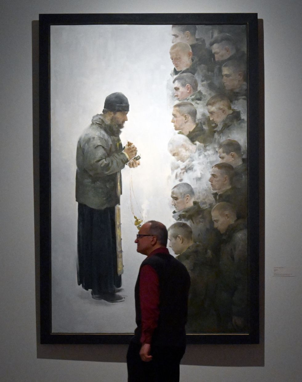 A visitor stands in front of 'Prayer Service' (2020) - an exhibition highlight - painted by Margarita Khvostova. Photo: AFP