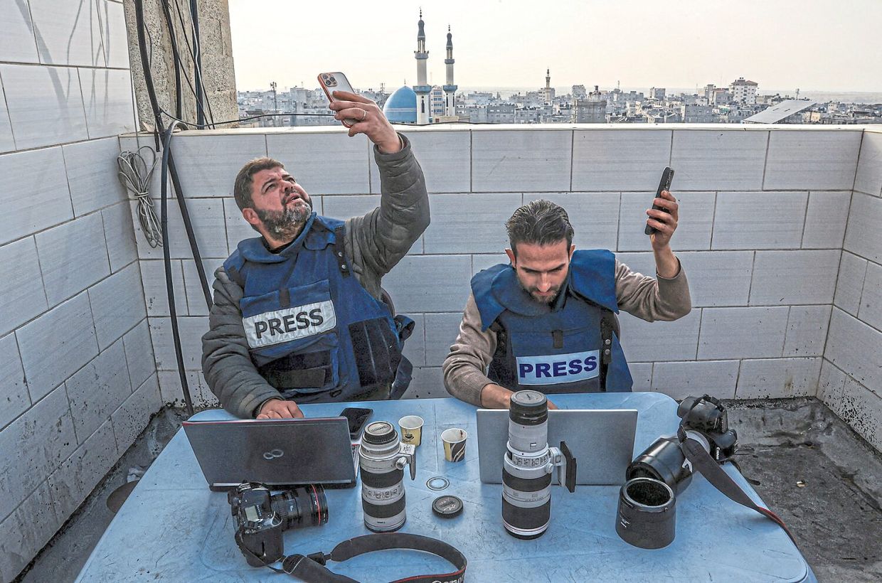 Palestinian journalists attempting to connect to the Internet using their phones in Rafah on the southern Gaza Strip in December 2023. — SAID KHATIB/AFP