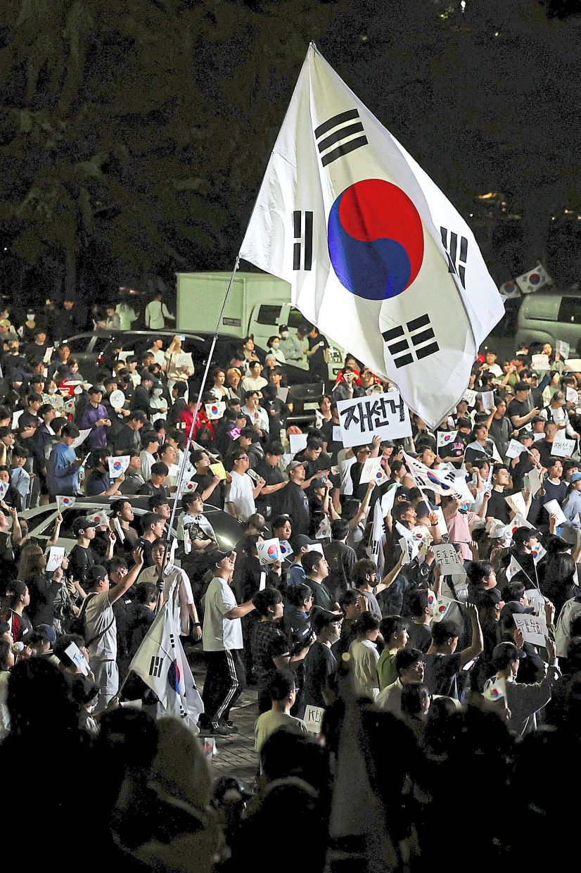 Time of distrust: A large South Korean flag flying over protesters in Seoul. — Reuters