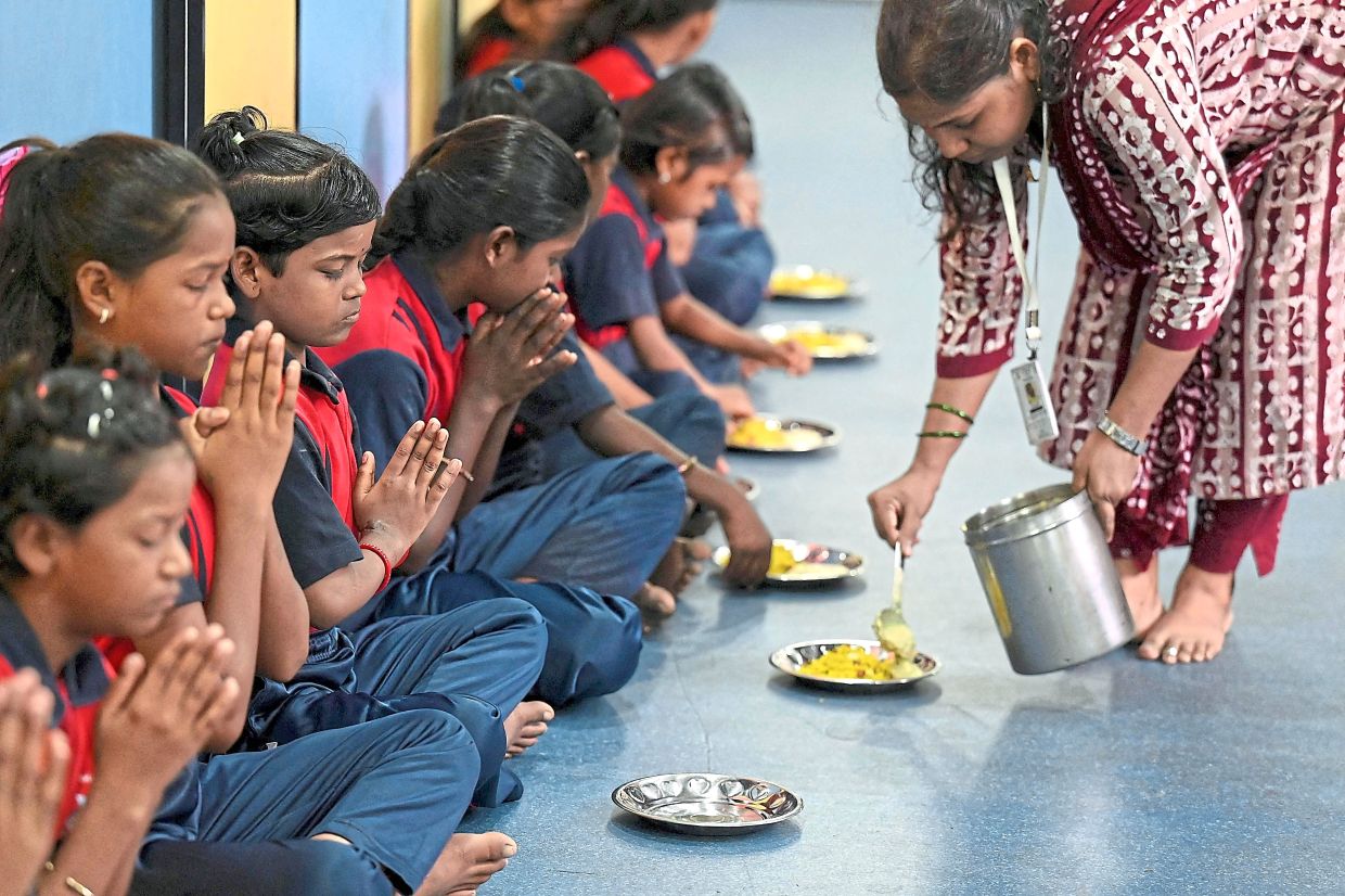 Fuel for the day: Students offering prayers before breakfast – the first of three free meals per day at the school. — AFP