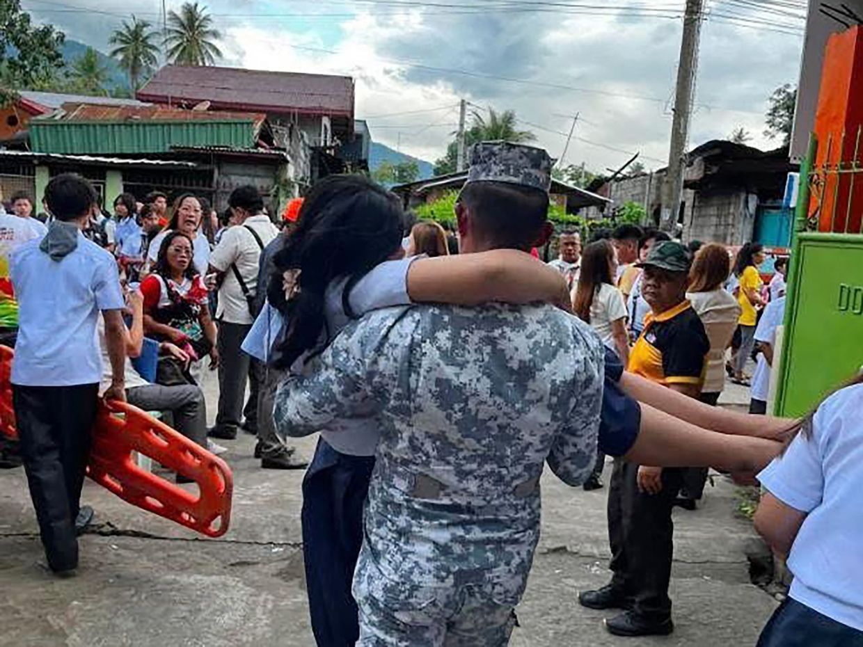 A Coast Guard serviceman carrying an injured student in Sta Cruz, Davao del Sur. - AFP