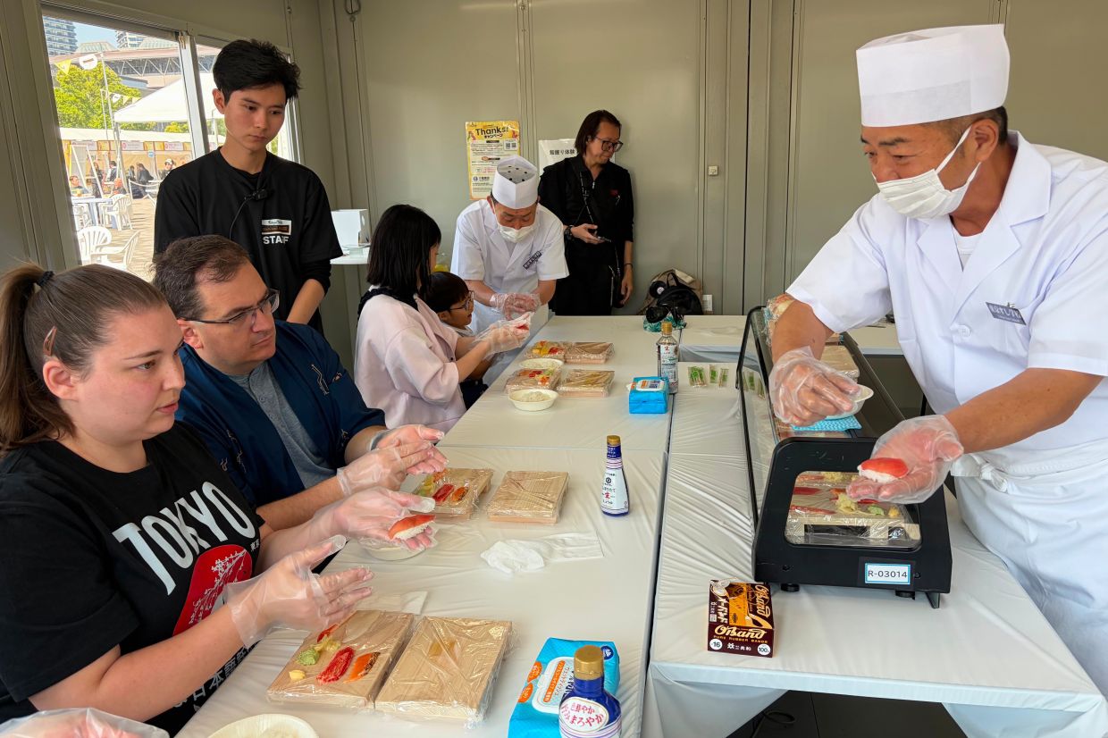 Brittany Nevins and her husband Kevin, both from Erlander, Ky., try making sushi for the first time with a sushi master in Tokyo.