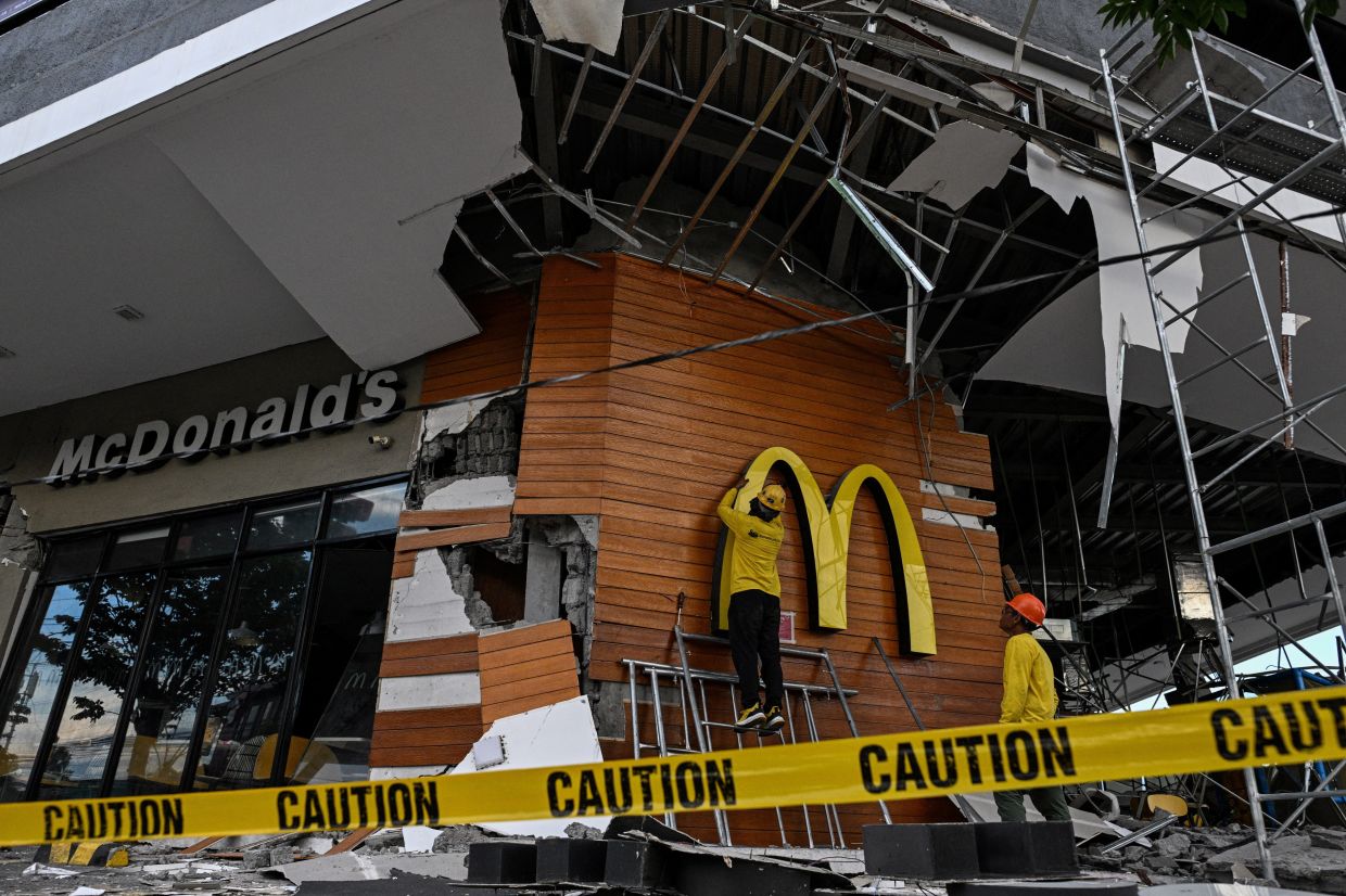 Workers removing a McDonald's logo a day after the earthquake in General Santos, southern Philippines on June 9, 2026. - Reuters