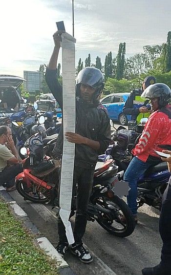 A motorcyclist displays a long list of summonses he received during the operation on Jalan Besar, Pasir Gudang.