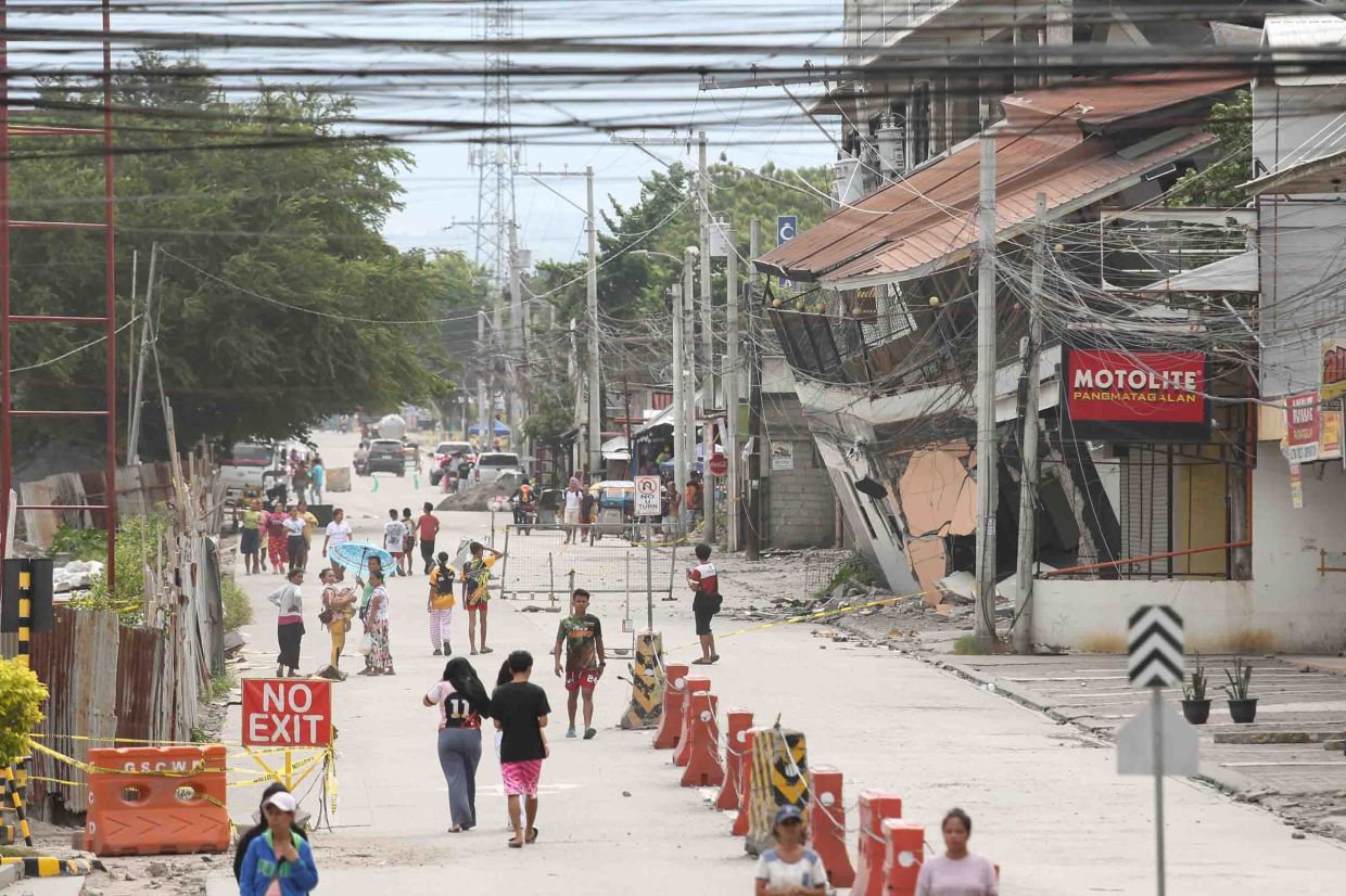 People walking past a collapsed building following the earthquake in Sarangani province, Philippines on June 10, 2026. - AP