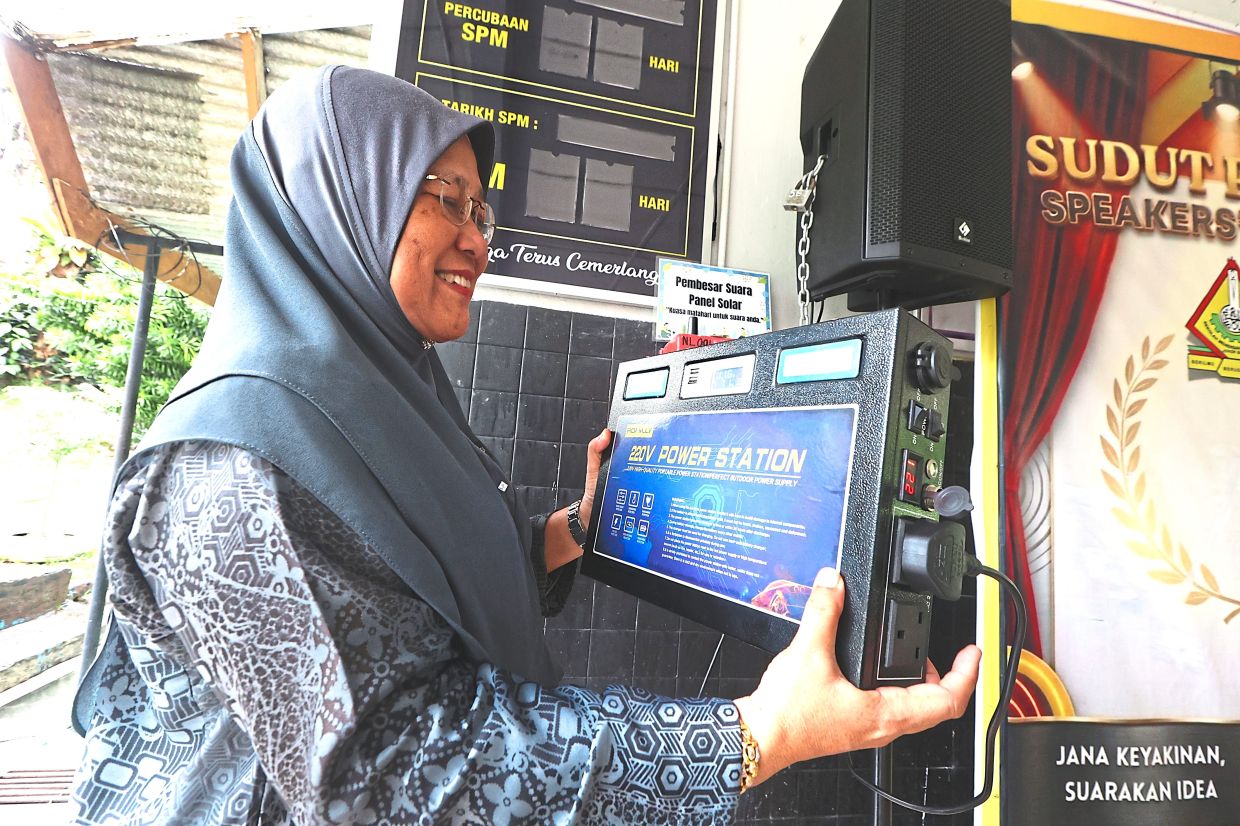 ​A teacher from SMK Taman Pelangi showcasing a portable solar power station used alongside a solar-powered PA system.