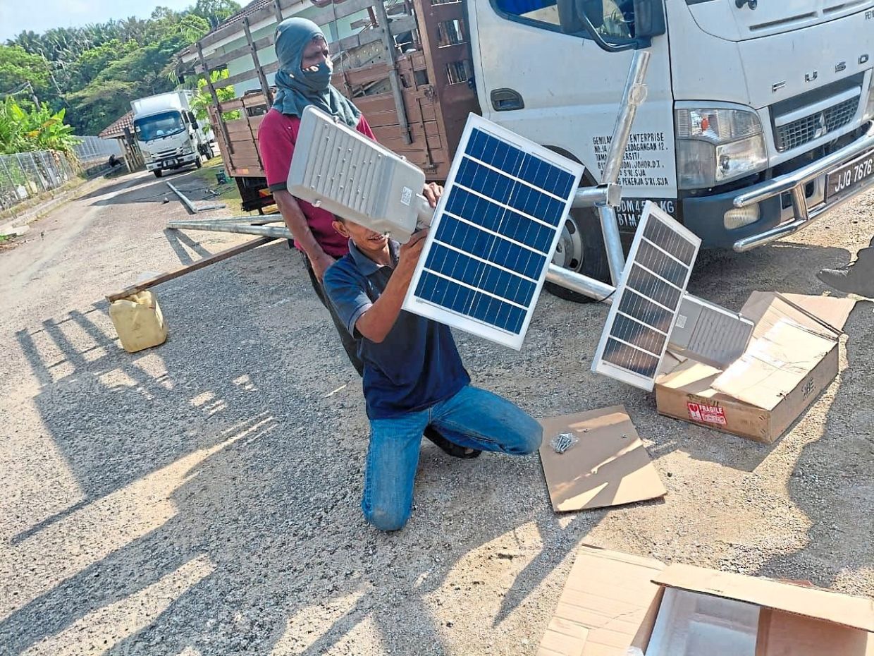 Workers preparing to instal smart sensor solar lights after SMK Mutiara Rini joined the MBIP solar energy initiative. — Courtesy of SMK Mutiara Rini