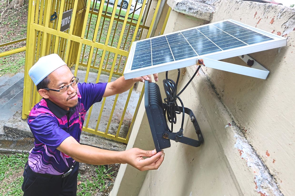 Hairul adjusting a compact solar panel setup used to power outdoor facilities in areas of SMK Taman Pelangi campus.
