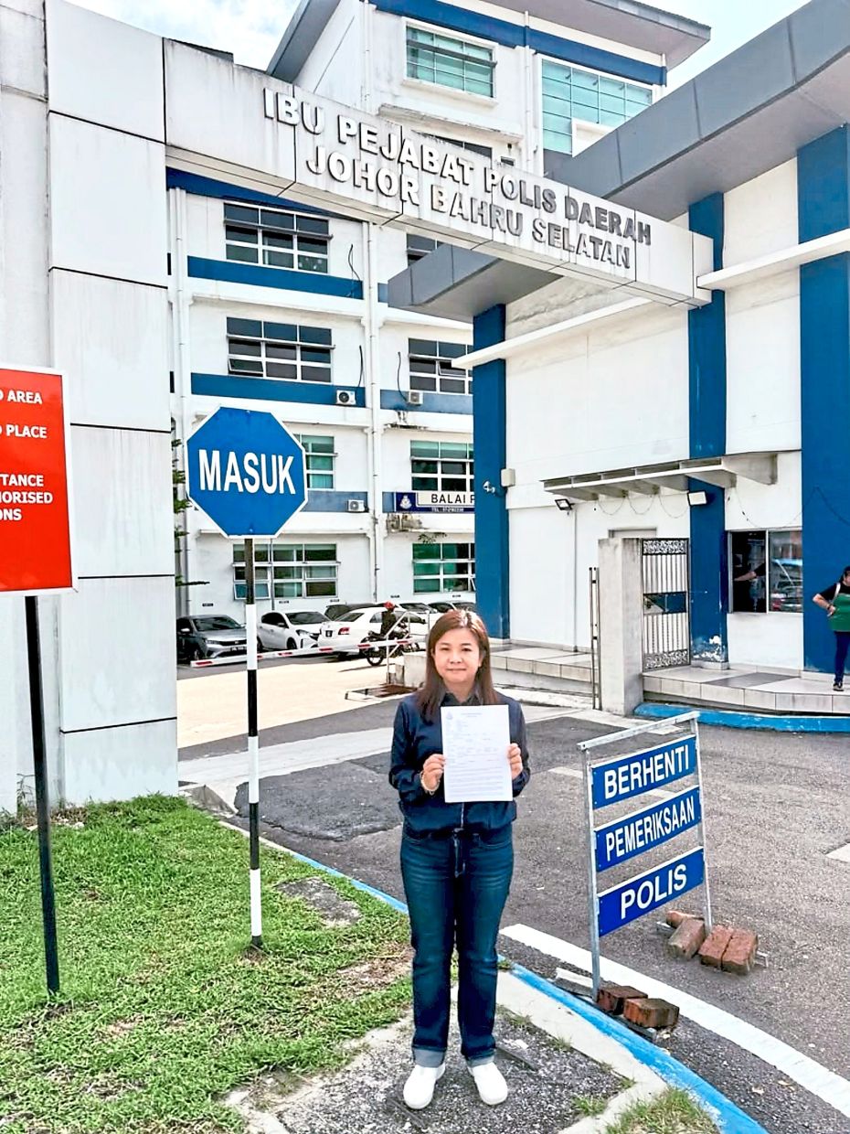 Teow holding up the report lodged at the Johor Baru South district police headquarters after the stray dog was run over and killed by the driver of a red pickup truck in Taman Puteri Wangsa. — Courtesy of Teow Chia Ling’s Facebook page