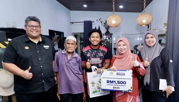 Norliza (second from right) presenting a replica of the WPP loan advance card worth RM1,500 to one of the students.