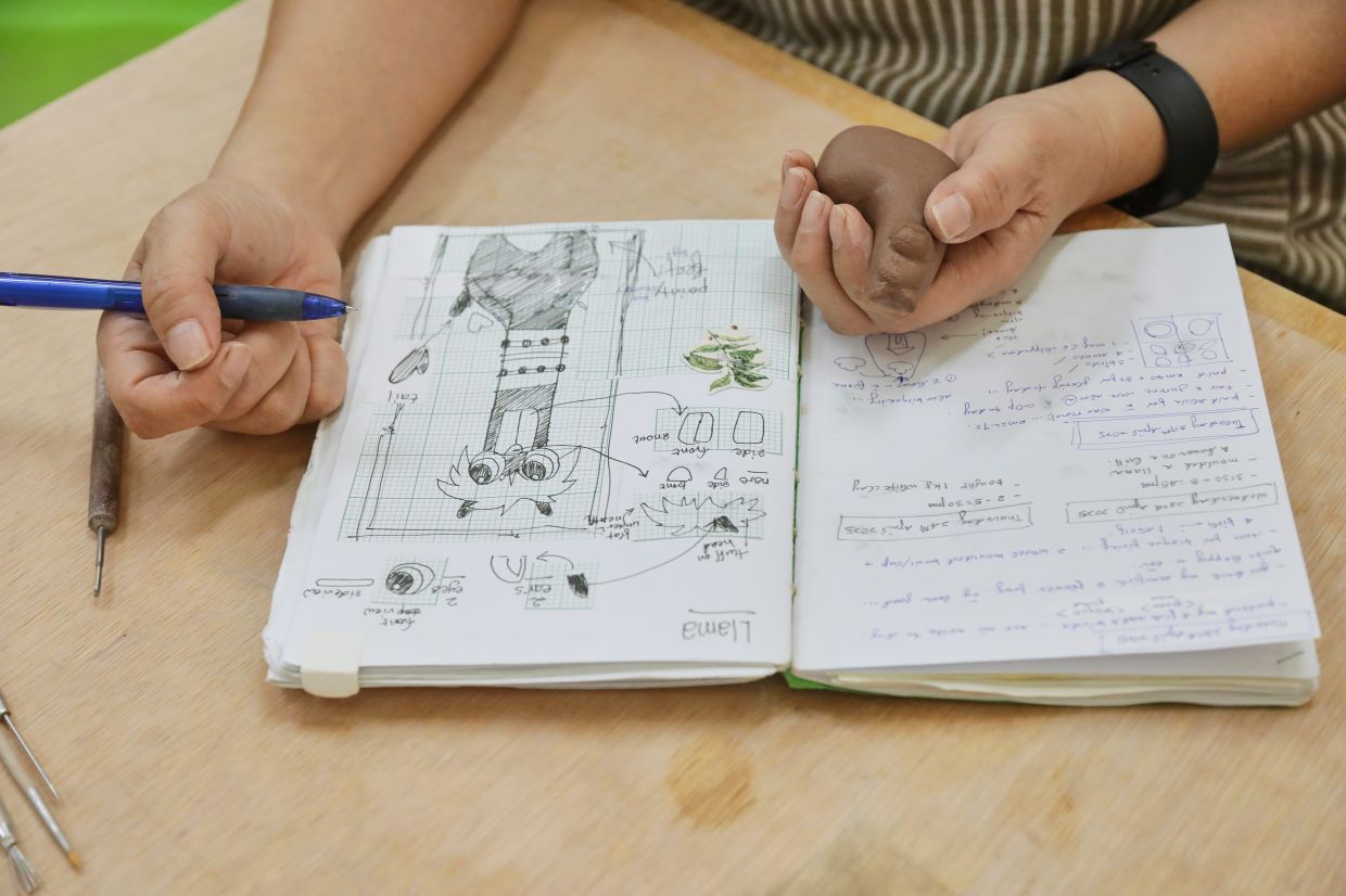 Tan sketches a design before transforming it into a clay figurine.