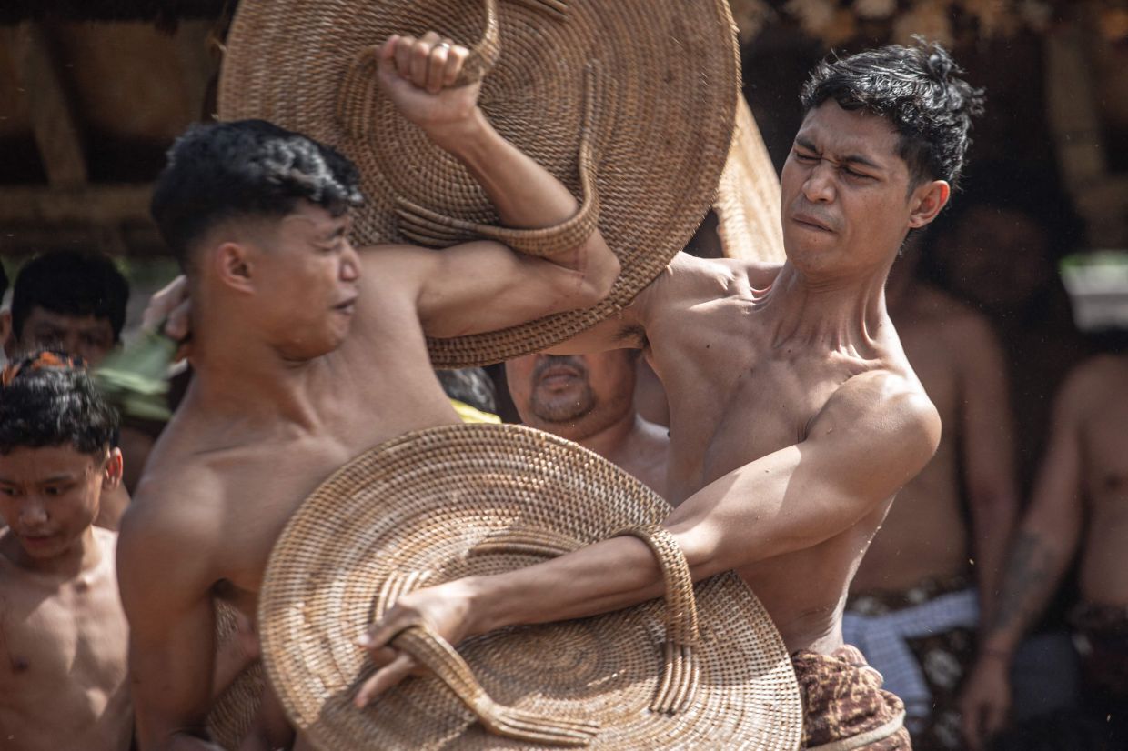 Villagers taking part in the annual 'Perang Pandan' (pandanus leaf fight) ritual, locally known as 'Mekare-kare', which honours Indra, the Hindu god of war, in Tenganan Pegringsingan, on Indonesia's resort island of Bali on June 11, 2026. - AFP