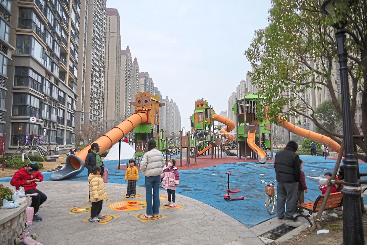 Residents playing with their children in a playground. - AP