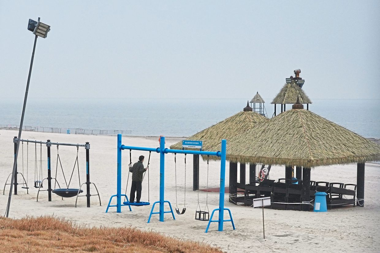 A man swinging on an empty beach at the semi-abandoned ‘Life in Venice’ housing complex. — AP