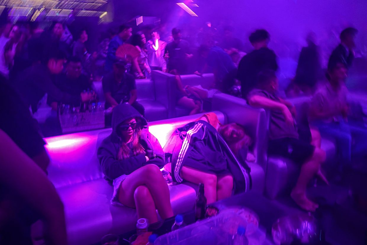People sleeping on a sofa in a nightclub in Yangon. In a blaring club on a big night out in wartime Myanmar, partied-out revellers doze until dawn by the dancefloor, wary of journeying home despite the end of a post-coup curfew. - AFP