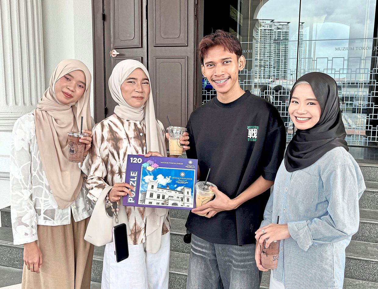 Akmal, pictured with his sisters and the puzzle set they redeemed after completing an activity booklet.
