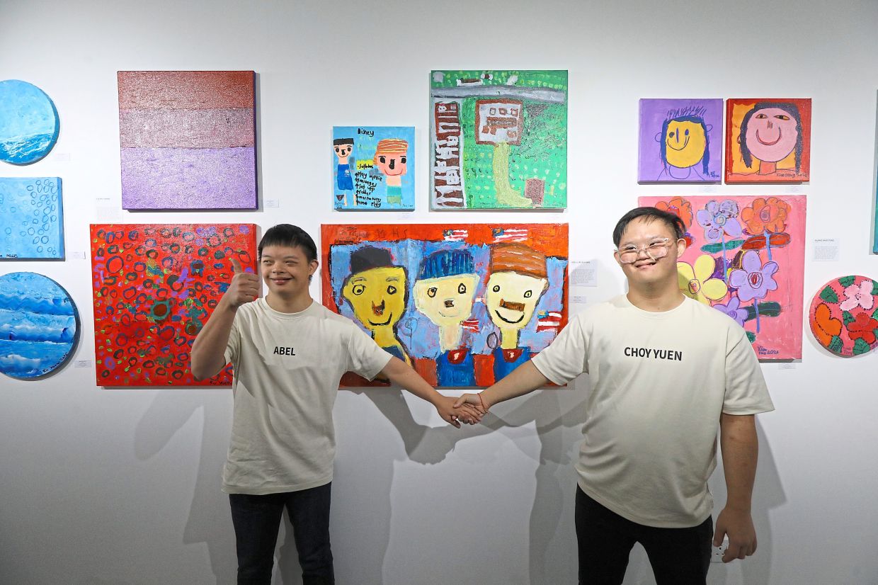 Abel Lim Jea Aan (left) in front of his artwork, hand-in-hand with See, alongside other works featured at the exhibition in Taman Tun Dr Ismail.