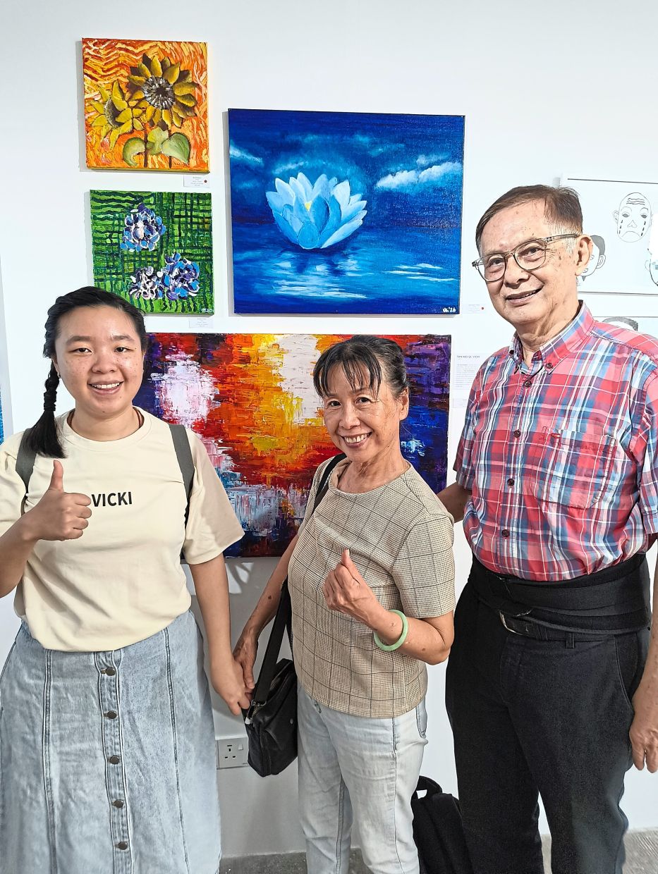Vicki with mother Lee Eng and father Song Poh in front of her paintings.