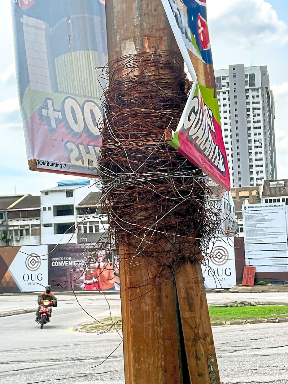 Rusted wire tightly wound around a utility pole along Jalan Kelang Lama, Kuala Lumpur, shows how illegal advertising continues to scar the city’s streetscape. — Bavani M/The Star