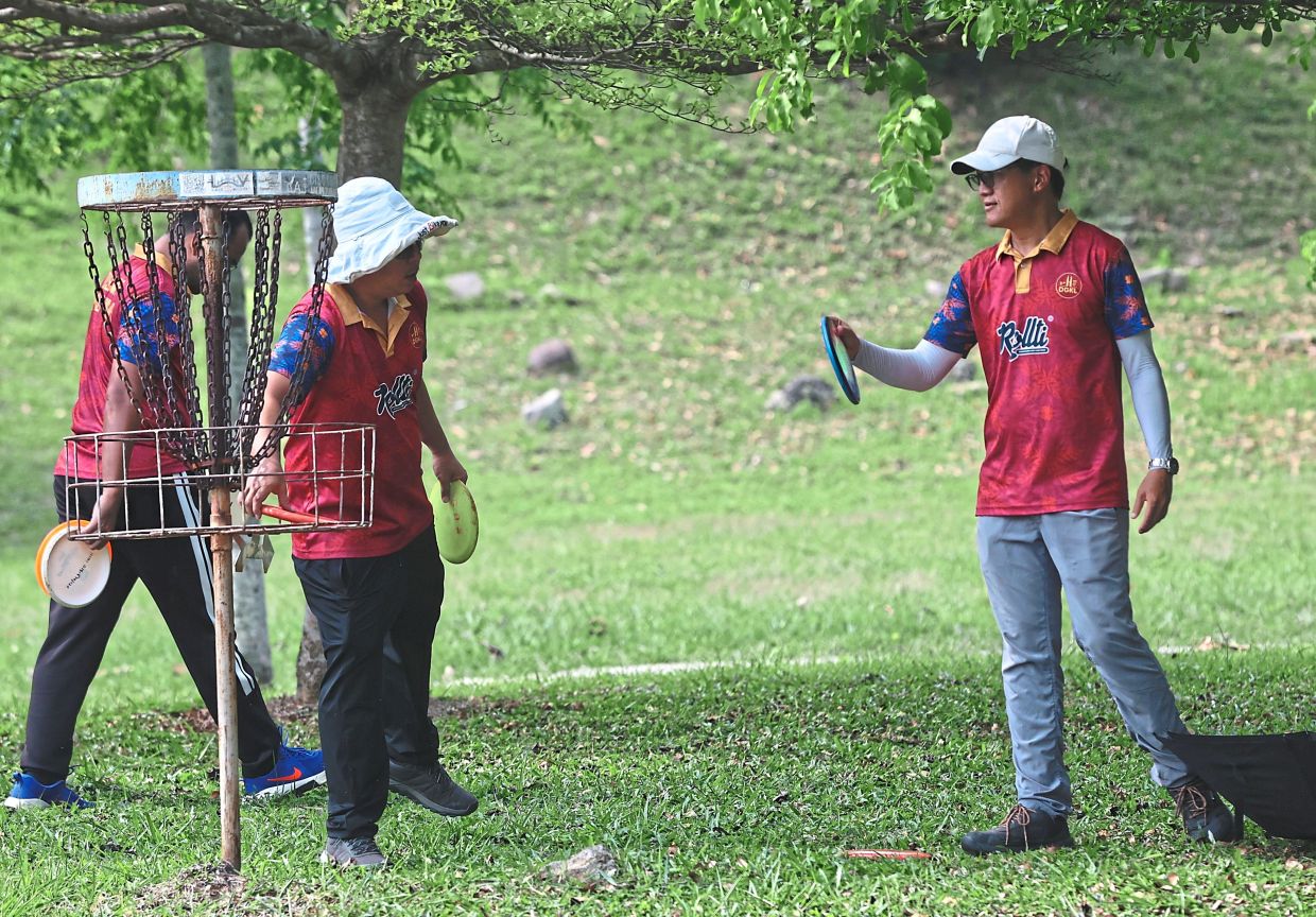 Players collecting their discs from metal baskets, which serve as targets in disc golf, during a game at Lake Valley.