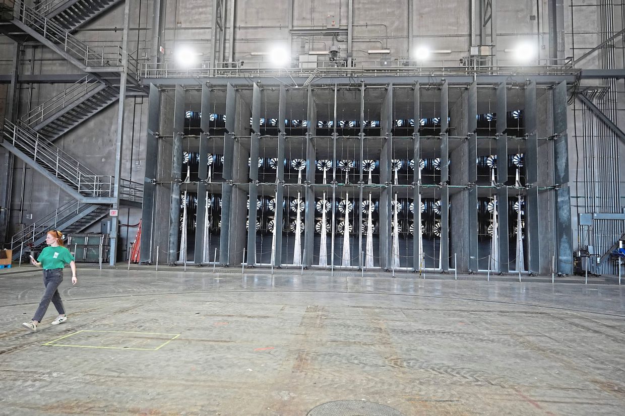 A person walks near fans used for wildfire research.