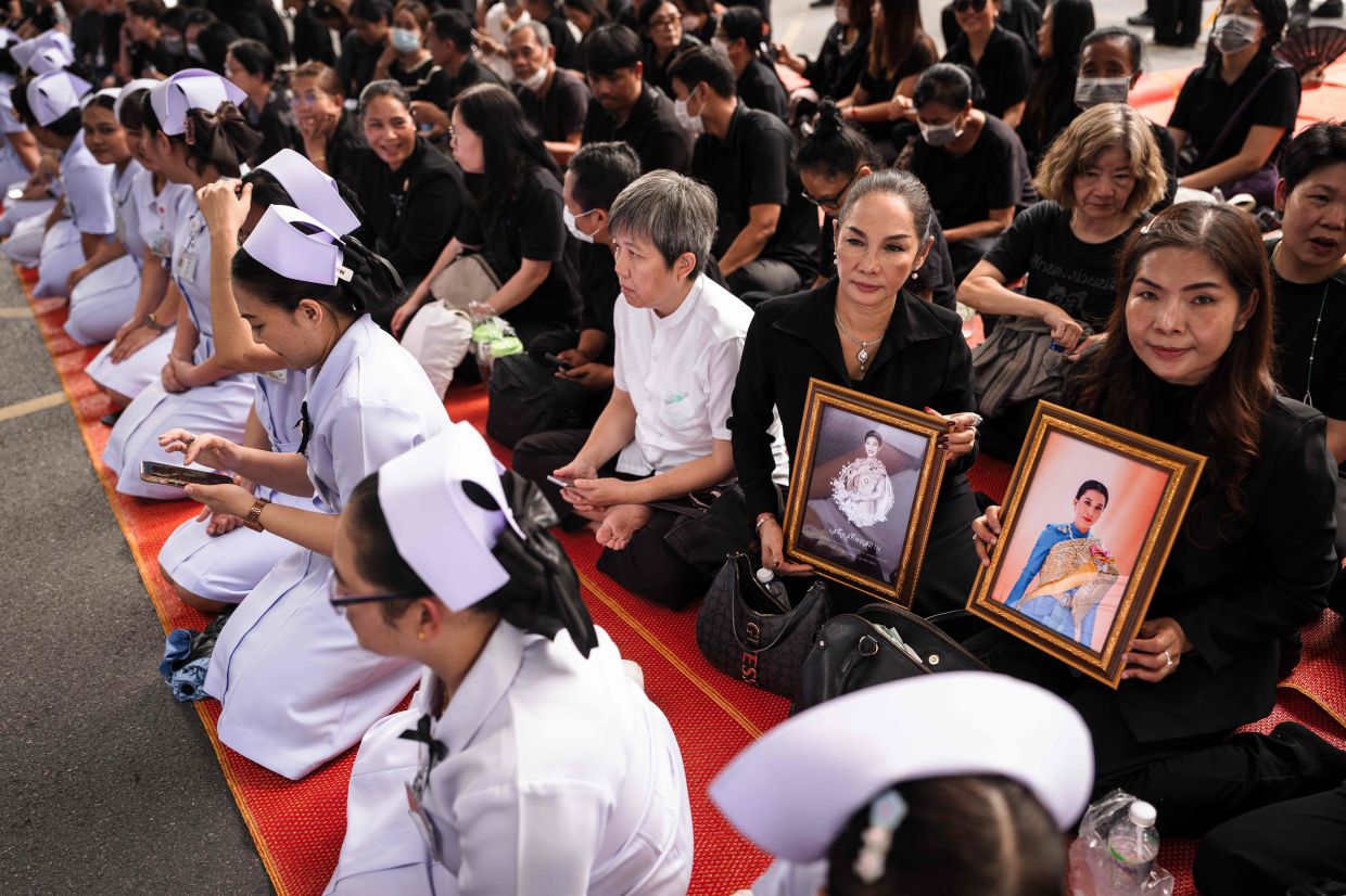Mourners holding portraits of Thai Princess Bajrakitiyabha Mahidol wait to pay their respects along a motorcade route, as her remains are set to be transported from Chulalongkorn Hospital to the Grand Palace for the start of funeral rites, in Bangkok on June 13, 2026. Hundreds of black-clad Thai mourners gathered at the royal palace in Bangkok on June 13, awaiting the arrival of the body of the king's eldest daughter, a day after her death was announced. -- Photo by Chanakarn Laosarakham / AFP)