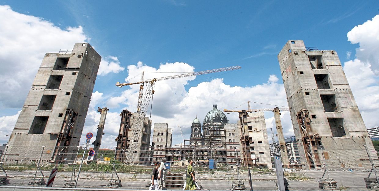 In August 2008, tourists in Berlin walk past the remaining part of the former Palace of the Republic. — WOLFGANG KUMM/dpa