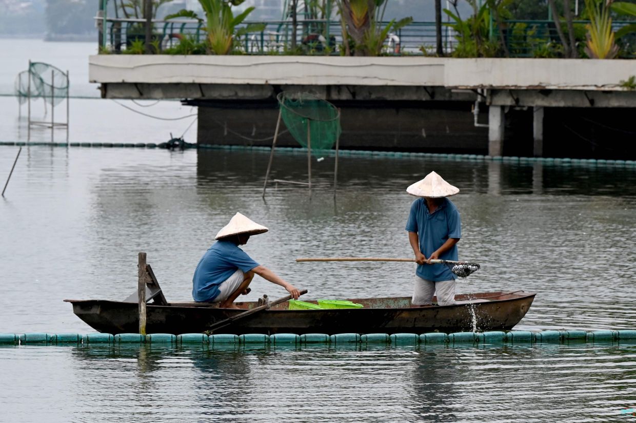Men on a boat retrieve sunken golf balls from West Lake in Hanoi on Monday, June 15, 2026. -- Photo by Nhac NGUYEN / AFP