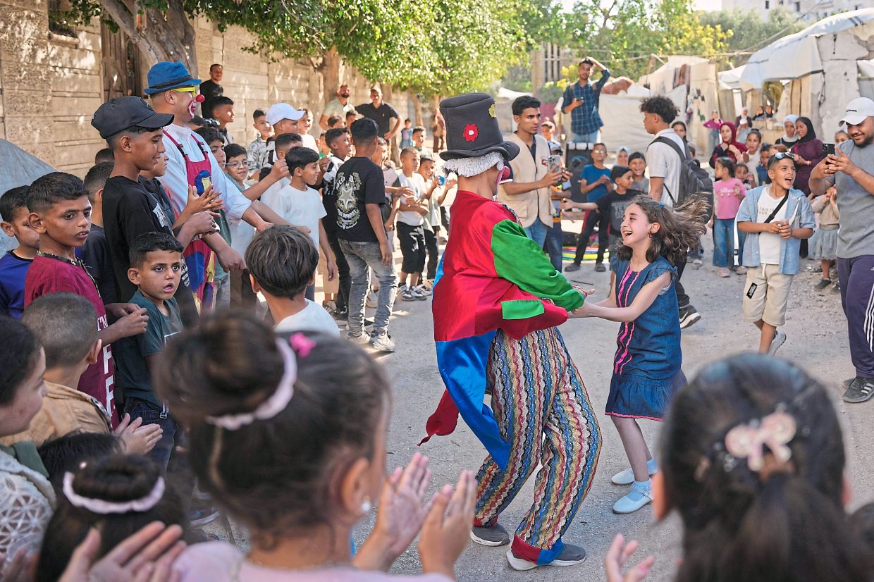 Palestinian clown Mohammed Salem, 18, dancing with a girl as he performs on a street during Aidiladha celebrations in Gaza City. — AP