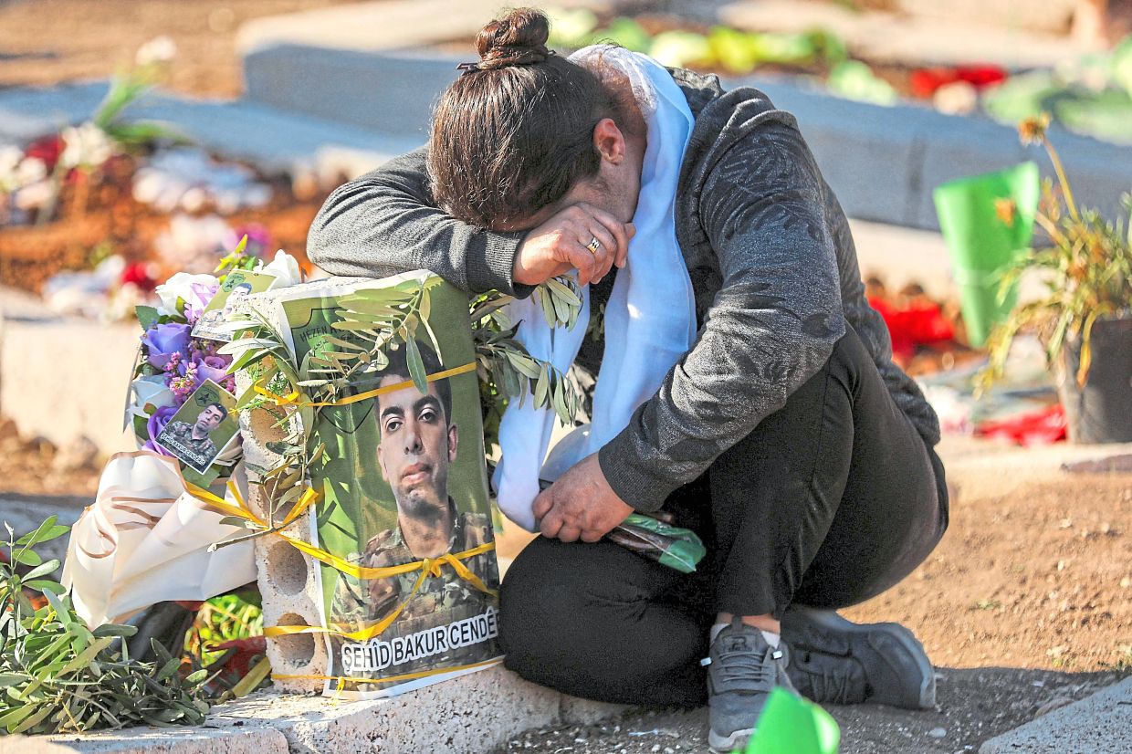 A woman grieving at the grave of a loved one, a Kurdish fighter, at a cemetery in Qamishli, Syria’s predominantly Kurdish northeast. — AFP