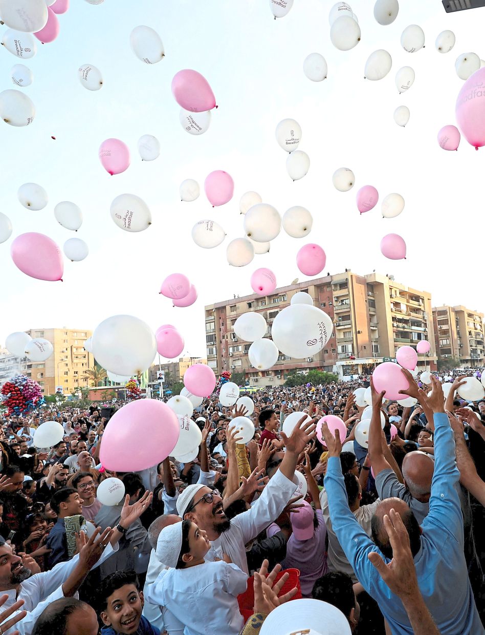 A crowd rushes to catch balloons released after Aidiladha prayers at a public park outside El-Seddik Mosque in Cairo, Egypt. — Reuters