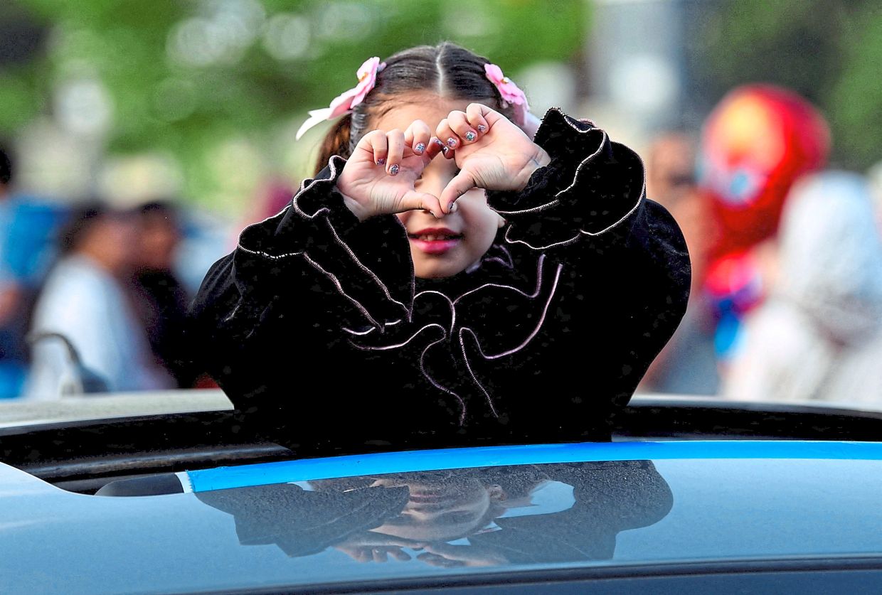 A girl forming a heart with her hands at a public park outside El-Seddik Mosque in Cairo, Egypt. — Reuters