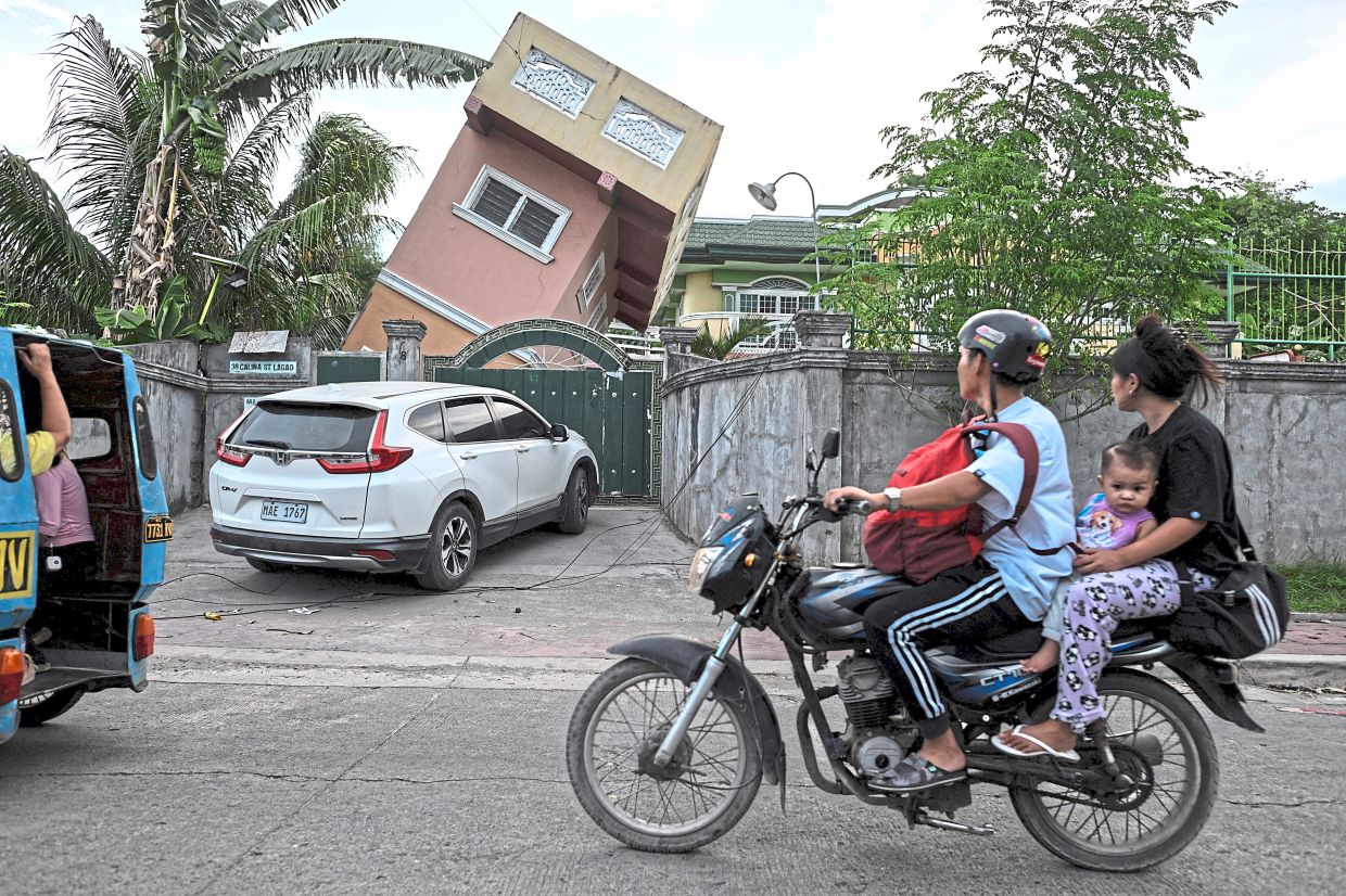 Motorists passing a house left precariously tilted, a stark reminder of the earthquake’s impact. — Reuters