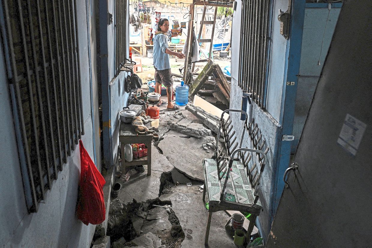 A resident gestures toward the extensive damage inflicted on a home by the powerful quake. — Reuters