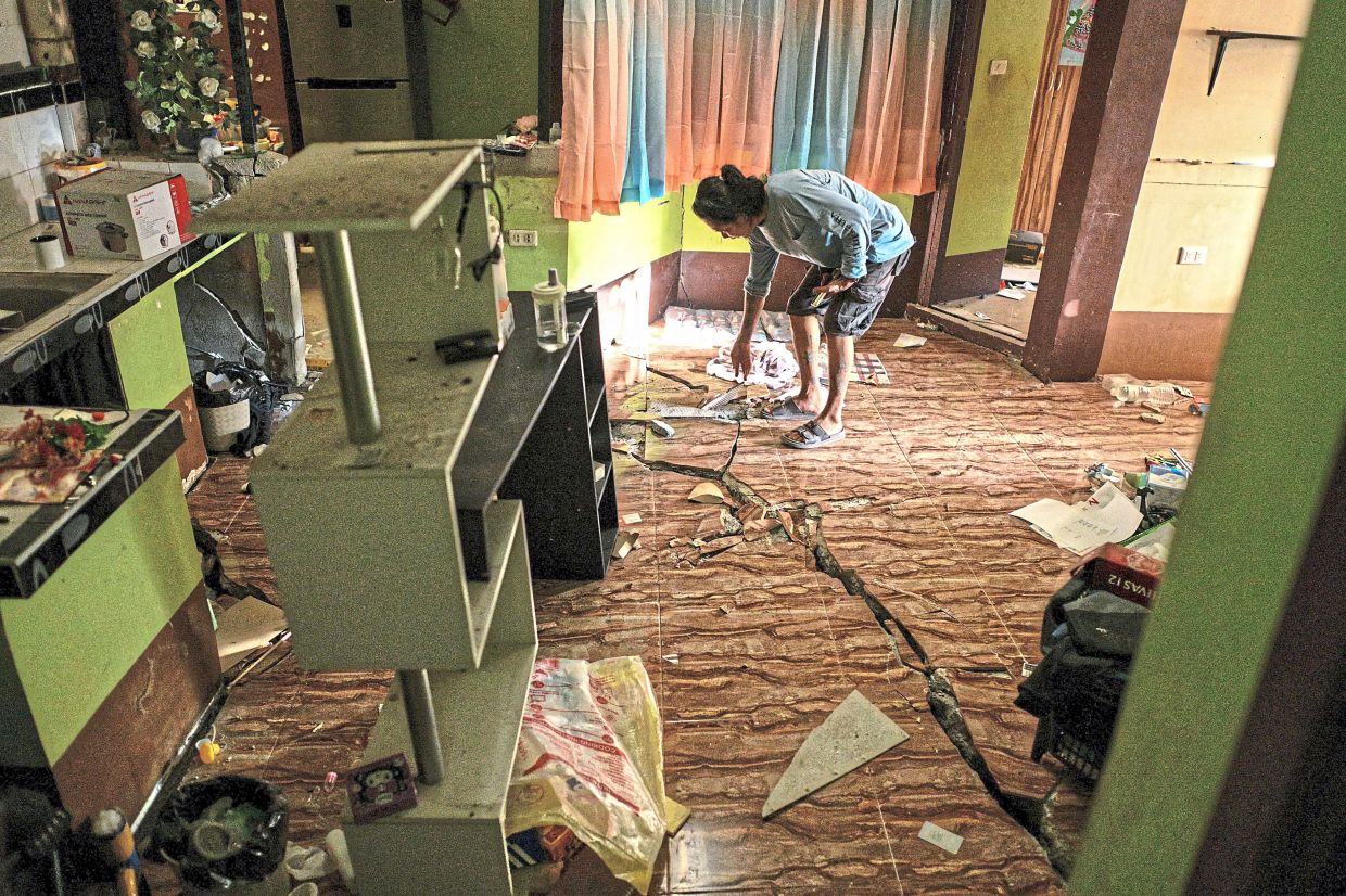 A man showing a gaping crack that split the floor of his home, revealing the quake’s destructive force a day after the magnitude 7.8 tremor in General Santos. — Reuters